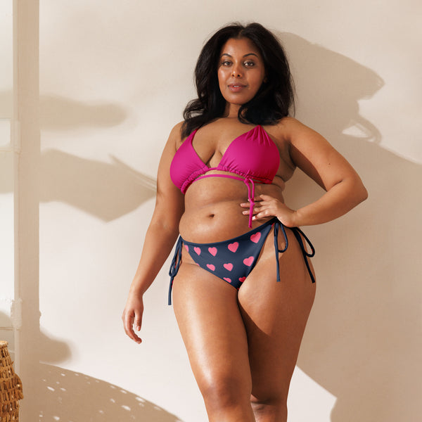 Confident model showcasing the comfort and style of our Recycled String Bikini with a vibrant magenta top and heart-patterned bottom.